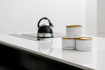 Kitchen storage canisters stacked with kettle on cooktop