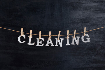 Obraz premium Word CLEANING hangs on the rope with clothespins against black background.