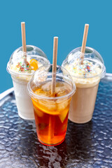 Summer drinks in plastic glasses with a lid and straws on the table. Take away. Concept. Poster.Photo