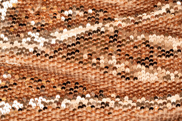 Fototapeta premium Golden shiny background, fabric background with sparkle. Sequins on the textile with folds. Close up