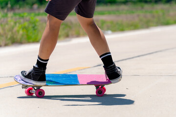 Fototapeta premium Close Up A young Asian man's legs are skateboarding on a country road on a sunny and clear day., Play surf skate.
