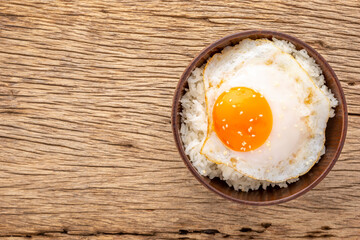 streamed rice with runny yolk fried egg and sesame on top on rustic natural wood texture background with copy space for text, top view