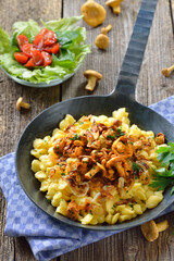 Schwäbische Spätzle mit  frischen, gebratenen Pfifferlingen und Zwiebeln in der Pfanne rustikal serviert - Vegetarian Swabian spaetzle with fried chanterelles and onions served in a frying pan