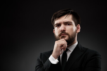 Serious businessman holding hand near face