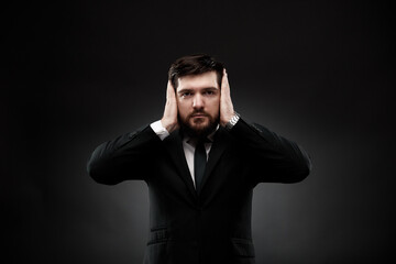 Businessman gesturing, closing ears with hands