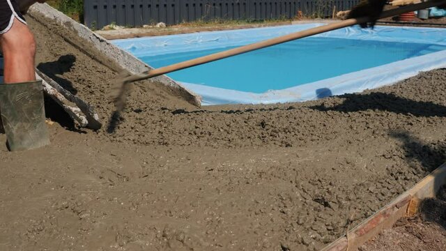 A team of builders produces concrete paving around the pool