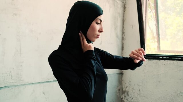 A beautiful arabian sports woman wearing national hijab is measuring her pulse while using a fitness tracker
