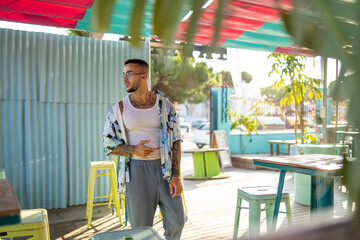 Chico joven tatuado vestido a la moda posando