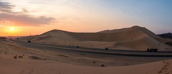 Fototapeta na wymiar Sand dunes in Badr, Madinah, Saudi Arabia at sunset with the highway running through them