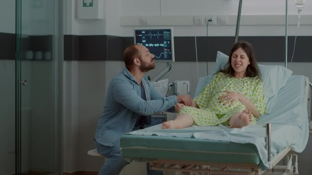 Woman with pregnancy and painful contractions in hospital ward asking for help from doctor or nurse. Nervous caucasian man overreacting about childbirth delivery agony and screaming