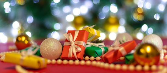 banner with multicolored Christmas gifts with blur Christmas balls and beads on bokeh background. Christmas background or Christmas card. New Year or Xmas concept. Copy space.