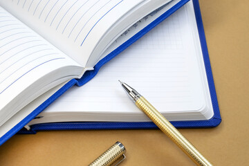 There is a yellow pen on two open notebooks with a blue cover. Business and educational concept