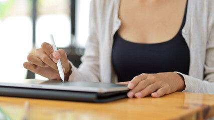 Close up front view of female using stylus pen with tablet for her graphic work