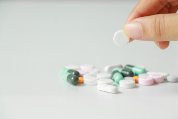 Woman hand holding pill on white background.