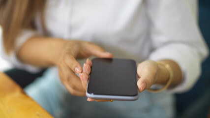 Female customer holding phone in her hands and waiting for pay stuff