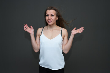 Photo of a girl with a smile in a white blouse posing with flying hair on a gray background.