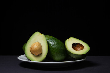 Avocado on a black background. Sliced avocado on a plate on a dark background