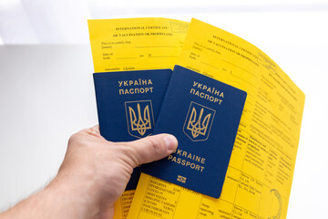 hand holding ukrainian passports with covid vaccination documents