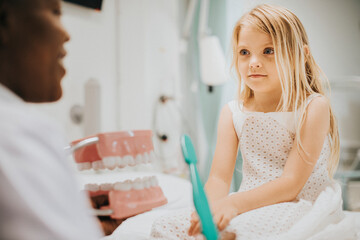 Dentist showing a young girl about dental hygiene