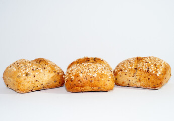 Baked bun soaked in sesame seeds and oatmeal isolated on white background. 