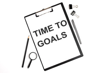 On a white background magnifier, a pen and a sheet of paper with the text TIME TO GOALS . Business concept