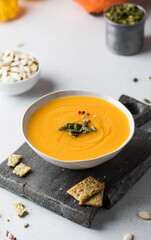 Pumpkin cream soup with seeds on a wooden board. Autumn dish.