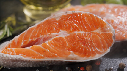 Close up view of seasoning process of salmon fillet. Spicing with salt, pepper, rosemary. European cuisine, delicious taste, professional cooking.