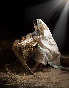 Mary sits in the stable near the manger with the baby