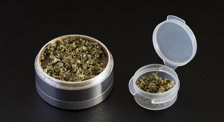 grinder with marijuana and transparent airtight container, black background