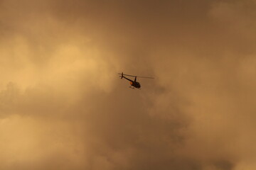 Helicopter in sky with orange clouds