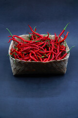 Red chili pepper in a bamboo basket isolated on a black background, focus selected