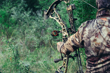 Man hunts in the forest with a bow. The hunter aims. 