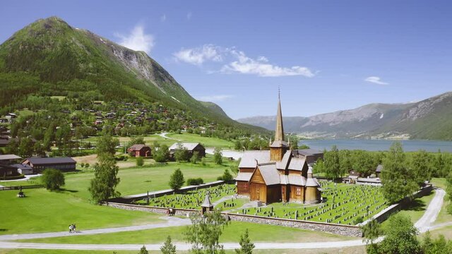 Lom Stave Church And Graveyard In Lom, Norway On A Fine Weather With Otta River In Background. aerial orbit