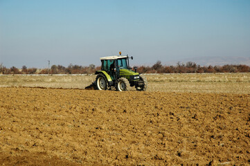 green tractor plows the field