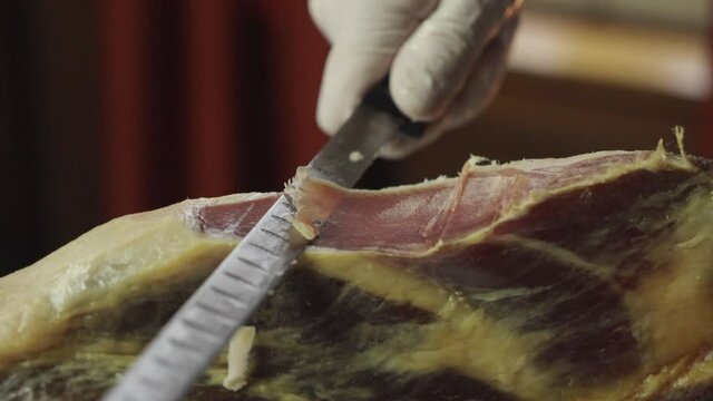 A chef in gloves cuts hamon with a knife. Close-up