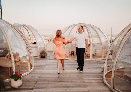 a man and a woman in love walk to a rooftop cafe on a date.