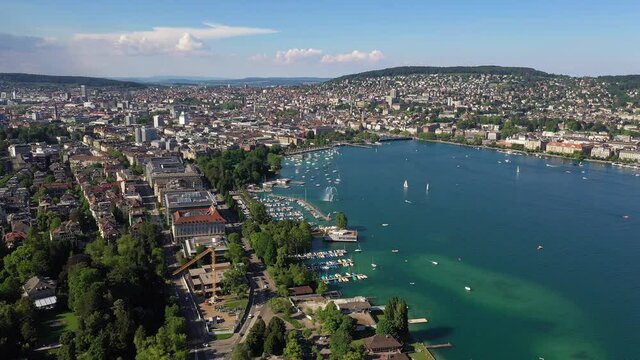 Aerial drone footage of the mythenquai leisure area bording the Lake Zurich with the Zurich city center in the background on a sunny summer day in Switzerland largest city. 