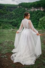 Fototapeta premium view from back. woman in a wedding dress posing in mountains. clothes for bride