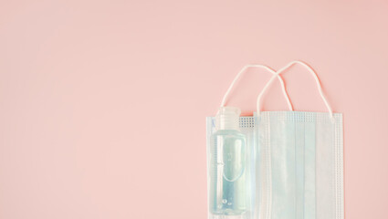 two medical face masks and bottle of blue alcohol gel on sweet pink background, campaign for...