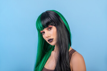 beautiful woman wearing colorful green black half wig against blue background