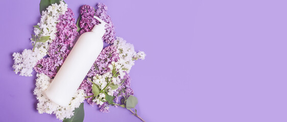 White bottle of natural herbal shampoo for women on white background. Beautiful lilac flowers. Beauty and care concept. Space for text
