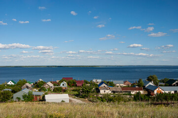 Fototapeta na wymiar View from the hill to the Russian village. On the background of the Volga River.