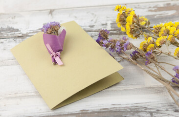 Naklejka na ściany i meble A bouquet of dried wild flowers with gift postcard on a white textured background made of antique wooden boards horizontal view from above