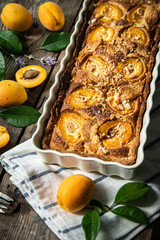 Apricot and frangipane tart in rectangular ceramic baking form on old wooden table.
