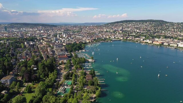 Aerial drone footage of the mythenquai leisure area bording the Lake Zurich with the Zurich city center in the background on a sunny summer day in Switzerland largest city. Shot iwith rotation motion