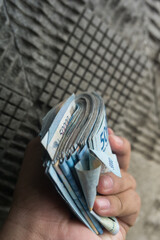 A rupiah note originating from Indonesia is being counted manually by hand consisting of fifty thousand denominations. For illustrations on economic-themed news, buying and selling, taxes, savings.