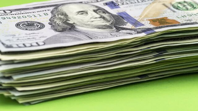 Wealth growth / earning money concept. Bundle of US dollars increases one by one bill, gradually turning into a big pile. Stop motion animation.