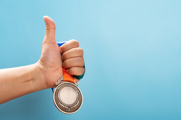 man lifting a bronze medal with the thumb up