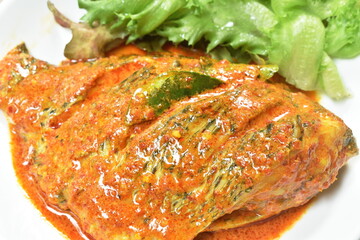 steamed mango fish dressing spicy coconut milk curry sauce on plate