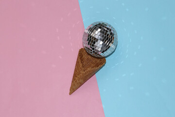 Disco ball ice cream in waffle cone on pink blue background. Minimal holiday party concept....